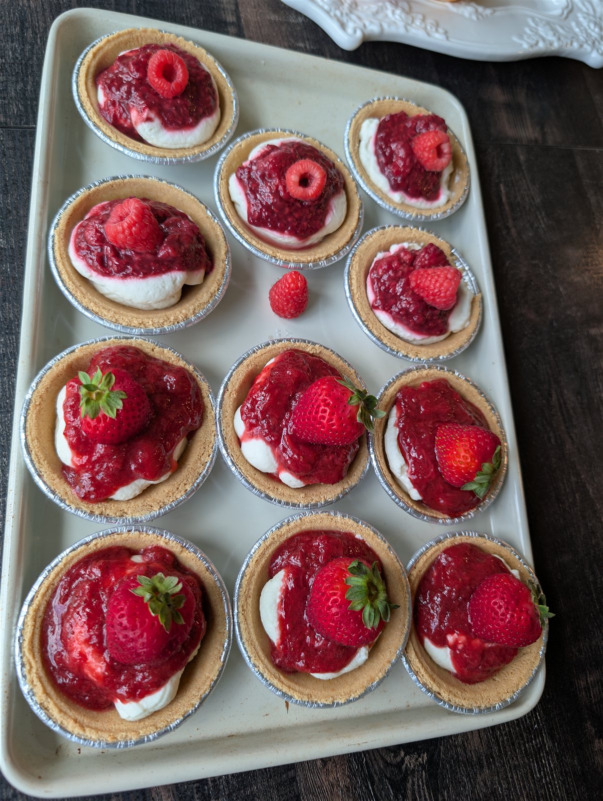 A full batch of mini cheesecakes topped with fresh fruit